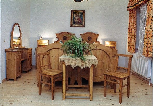 Rustikales Schlafzimmer mit Holzmöbeln, einem Doppelbett, einem Tisch mit Pflanze und einem Spiegel.