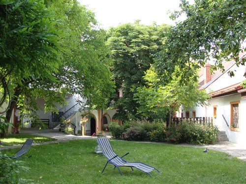 Ein grüner Innenhof mit Liegestühlen und Bäumen, umgeben von Gebäuden.